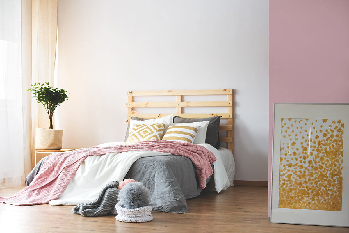 Testiera letto fai da te con bancali in questa camera con parete bianca e rosa.